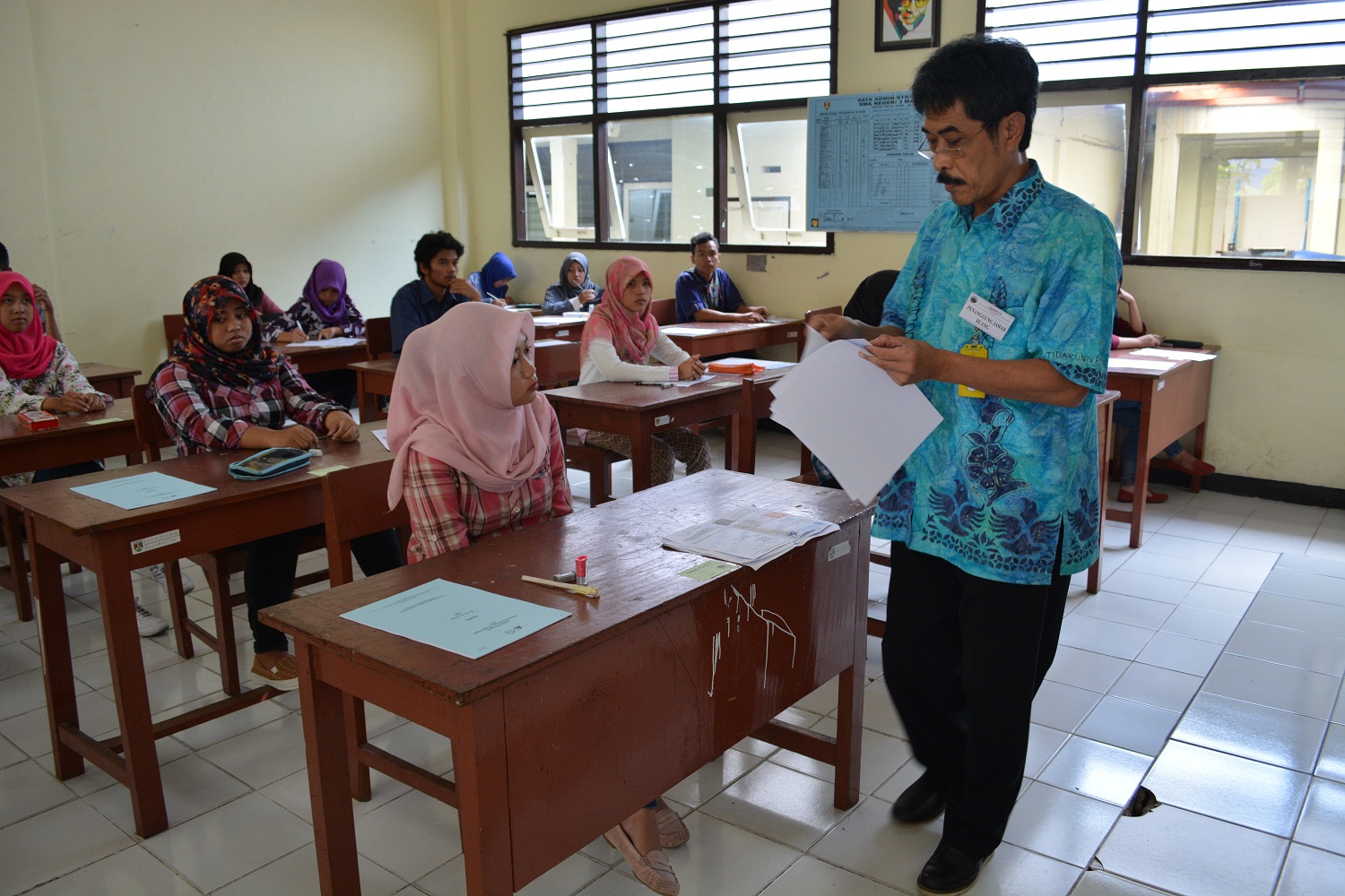 Drs. Lorentino Togar Laut, salah satu pengawas ujian di SMA N 3 Magelang sedang membagikan LJK dan soal ujian.